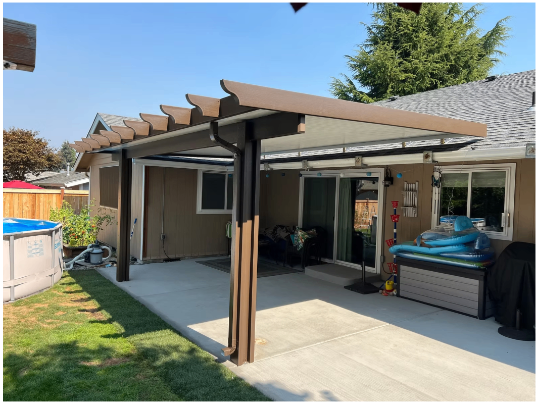 Wood-grain aluminum patio cover with embossed finish and decorative rafter tails on a residential patio.